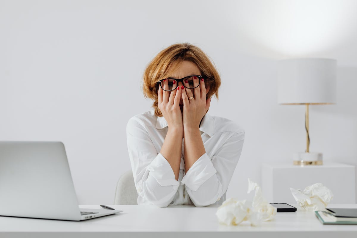 Persona con las manos en el rostro sentada frente a una laptop