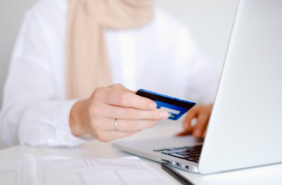 Persona usando una tarjeta azul para pagar desde una laptop
