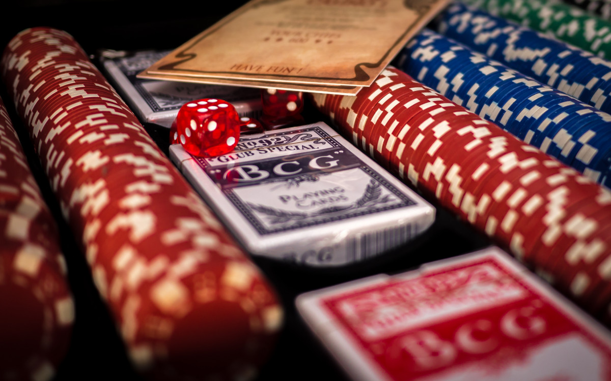 Fichas de casino junto a cartas sobre una mesa de juego
