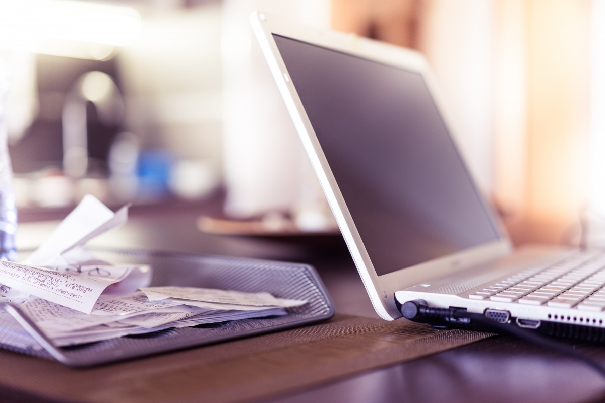 Recibos y papeles desordenados junto a una laptop