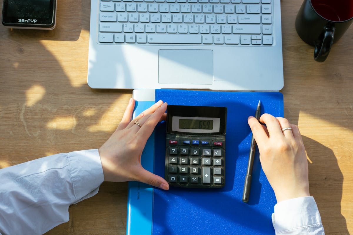 Calculadora y carpeta azul sobre un escritorio con documentos
