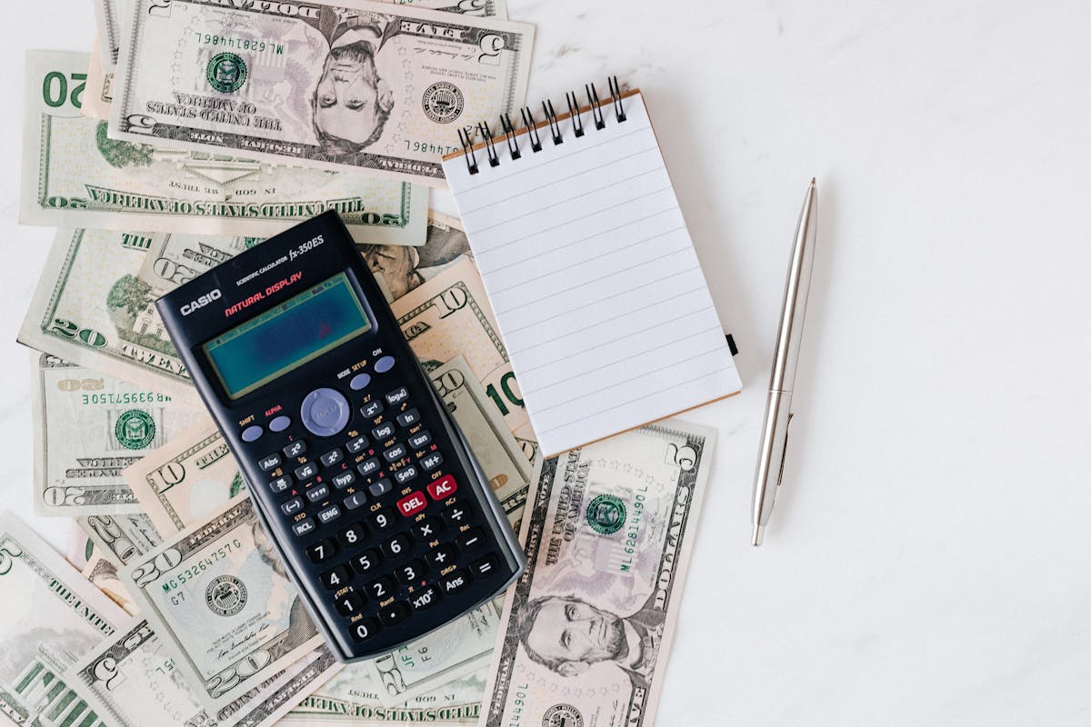 Mesa con calculadora, cuaderno, billetes y materiales de presupuesto